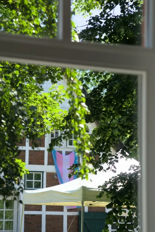 Eine Trans Pride Flagge hängt aus einem Fenster.